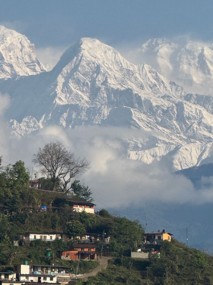 Stunning view of Himalayan peaks and lush village in Nepal, capturing nature's grandeur.